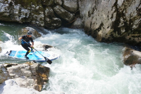 Paddleboardist overcoming drop on a river