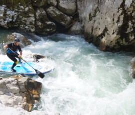 Paddleboardist overcoming drop on a river