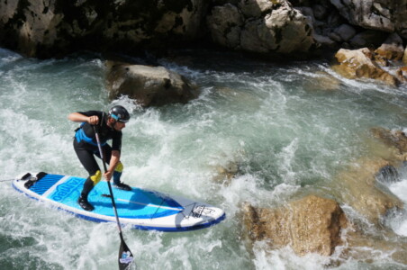 Whitewater SUP rider is navigating between rocks in Austria