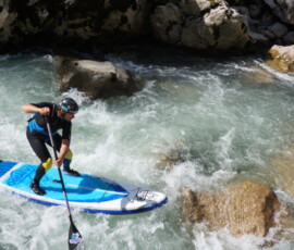 Whitewater SUP rider is navigating between rocks in Austria