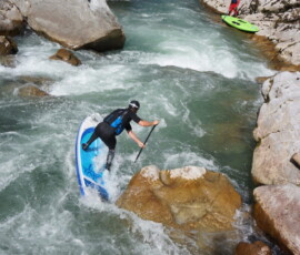SUP whitewater rider leaning on paddle