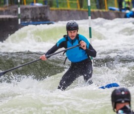 Splouvání na paddleboardu mezi slalomovými brankami.