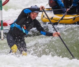 Paddleboardista v extrémním úseku používá pádlo ke stabilizaci.